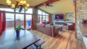 A spacious living area with a stone fireplace, leather sofas, and a wooden dining table. - Prairie-style Home on Garden Bay w/ Deck + Hot Tub (Garden)