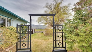 Una reja de metal negro con un sendero de piedra que conduce a una casa con techo azul.