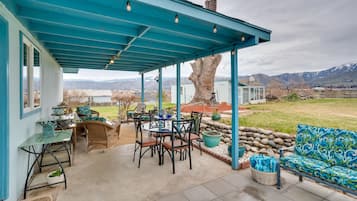 Relax on the covered patio with a dining set, sofa, and seating areas amidst a serene mountain view.