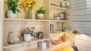 Een houten plankenwand met verschillende planten, boeken en een lamp.