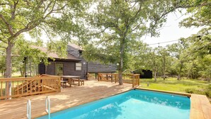 A wooden deck with a swimming pool, surrounded by trees and a small building with a wooden exterior. - Somerville Cabin w/ Private Pool! (Somerville)