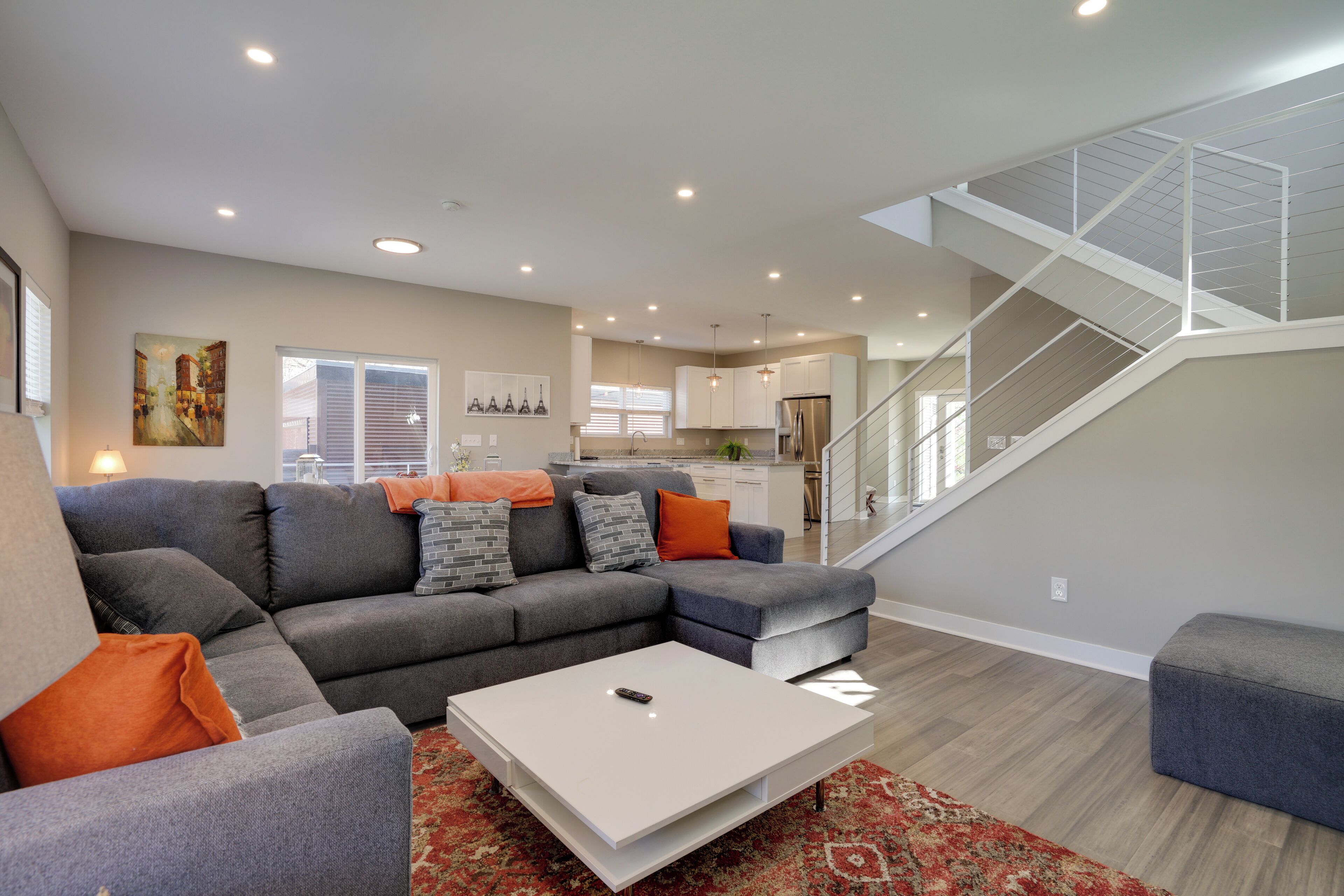 Un salon moderne avec un canapé d’angle, une table basse et un escalier menant à un niveau supérieur.