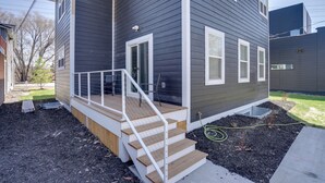 A two-story house with a wooden deck and a small front porch. - Spacious Minneapolis Vacation Rental w/ Game Room! (Minneapolis)