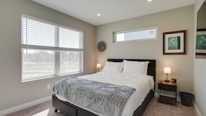 A bedroom with a large bed, a nightstand with a lamp, a small table, and a wall-mounted clock. - Spacious Minneapolis Vacation Rental w/ Game Room! (Minneapolis)