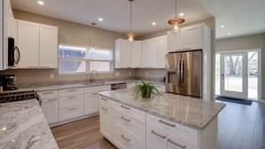 A modern kitchen with white cabinetry, granite countertops, stainless steel appliances, and pendant lighting. - Spacious Minneapolis Vacation Rental w/ Game Room! (Minneapolis)
