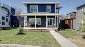 A two-story house with a covered porch and a small lawn. - Spacious Minneapolis Vacation Rental w/ Game Room! (Minneapolis)