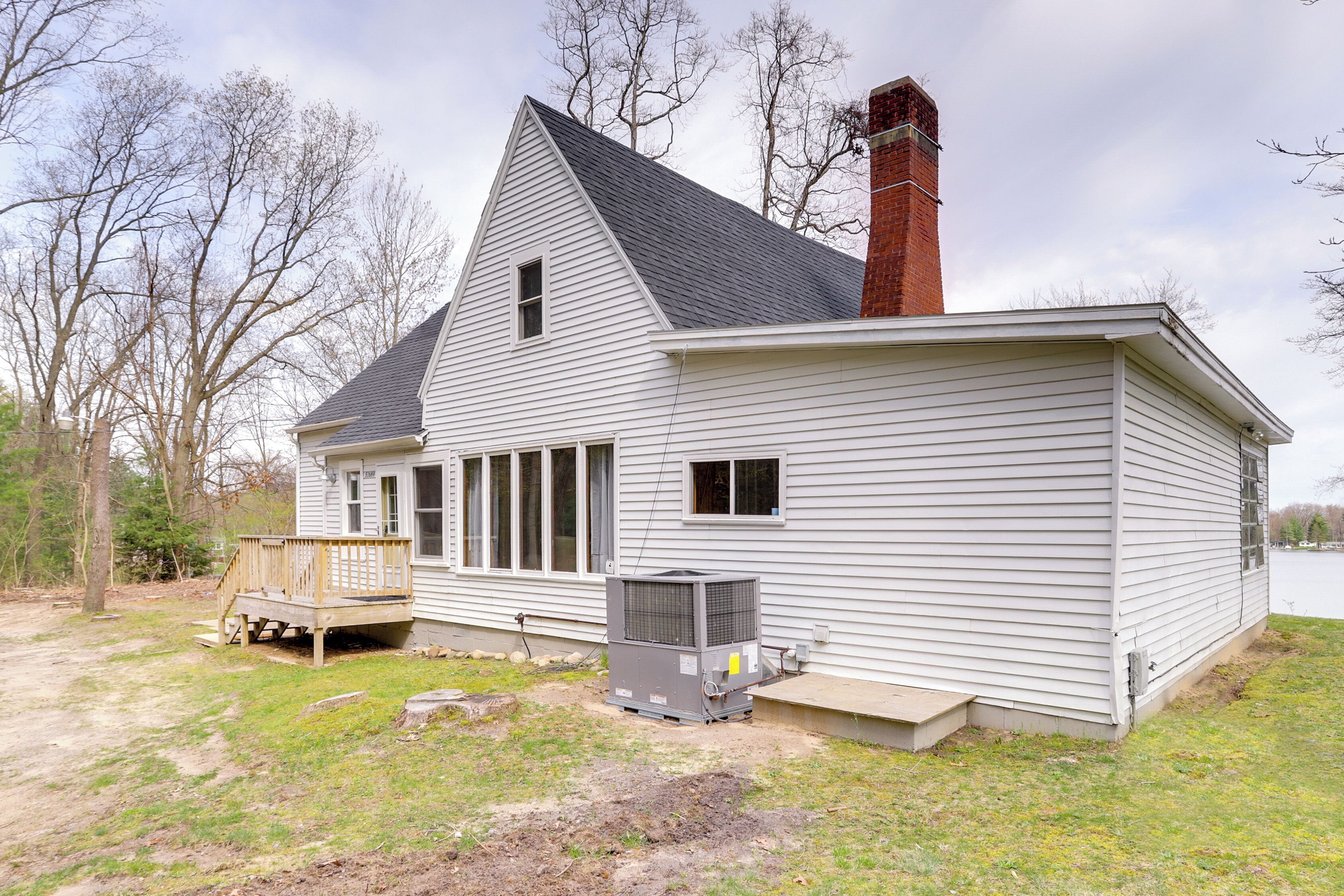 A single-story house with a gabled roof, a chimney, and a small deck.