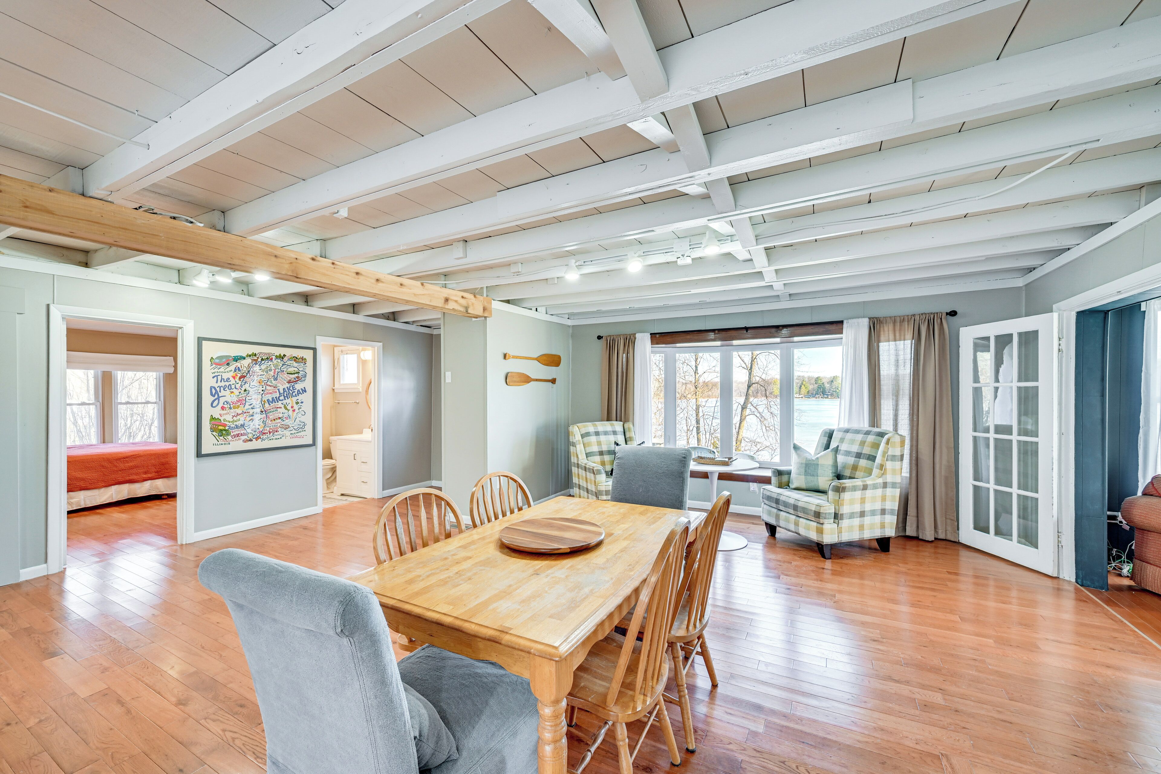 A spacious room with a wooden dining table, chairs, and a large window.
