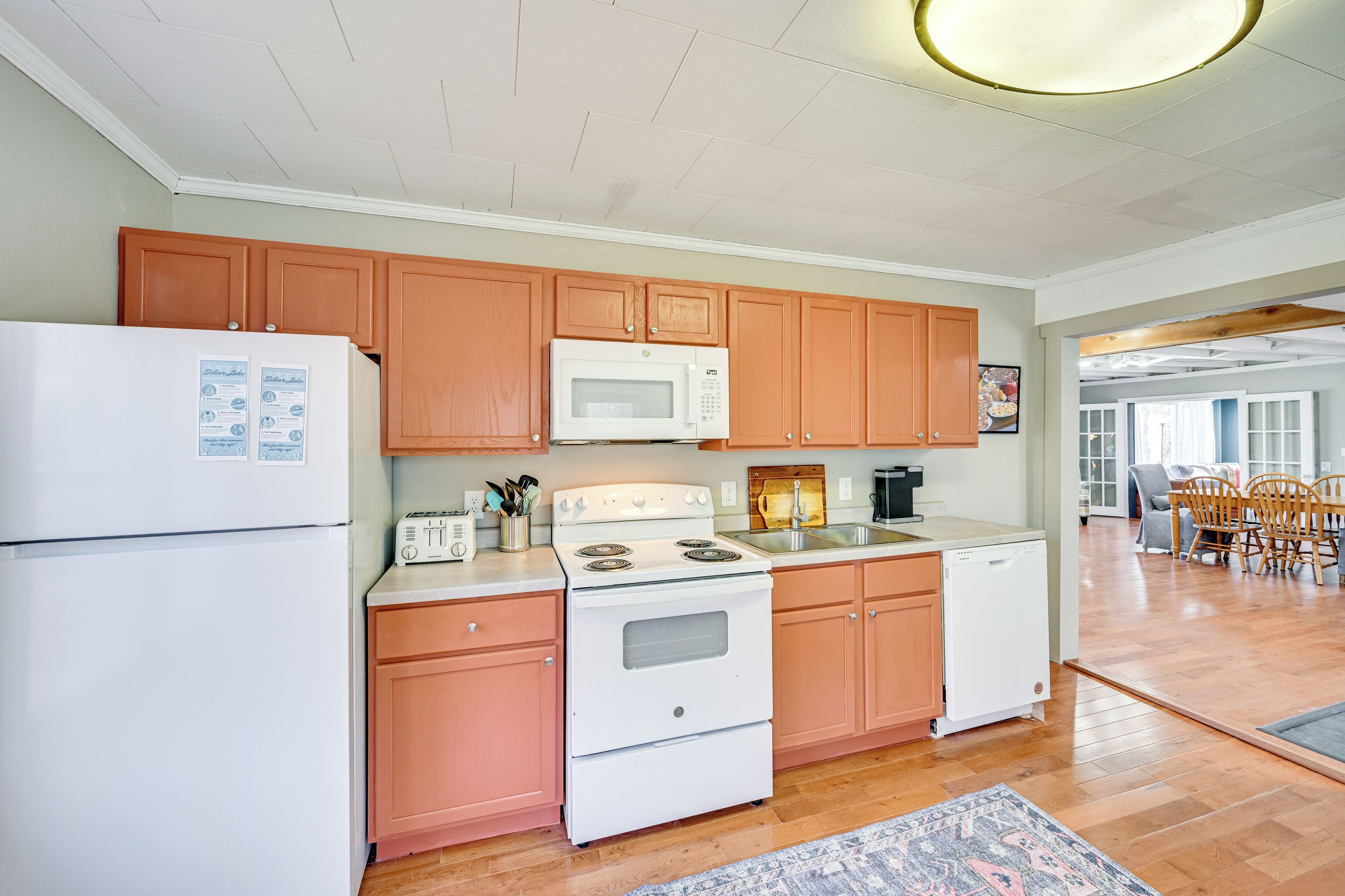 A kitchen with wooden cabinets, a white refrigerator, a microwave, a stove, and a dishwasher.