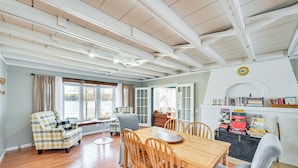 A dining area with a wooden table and chairs, a sofa, and a bookshelf with books. - Grand Junction Lake Home: 13 Mi to South Haven! (Grand Junction)