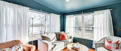 Una sala de estar con techo azul, un ventilador de techo, un sofá, un sillón y una mesa de centro.