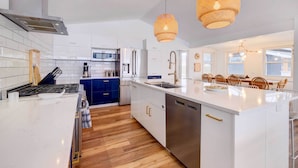 A modern kitchen with white cabinetry, a stainless steel dishwasher, and a blue island. - East Jordan Vacation Rental on Lake Charlevoix! (East Jordan)