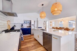 Uma cozinha moderna com armários brancos, eletrodomésticos de aço inoxidável e uma ilha central.