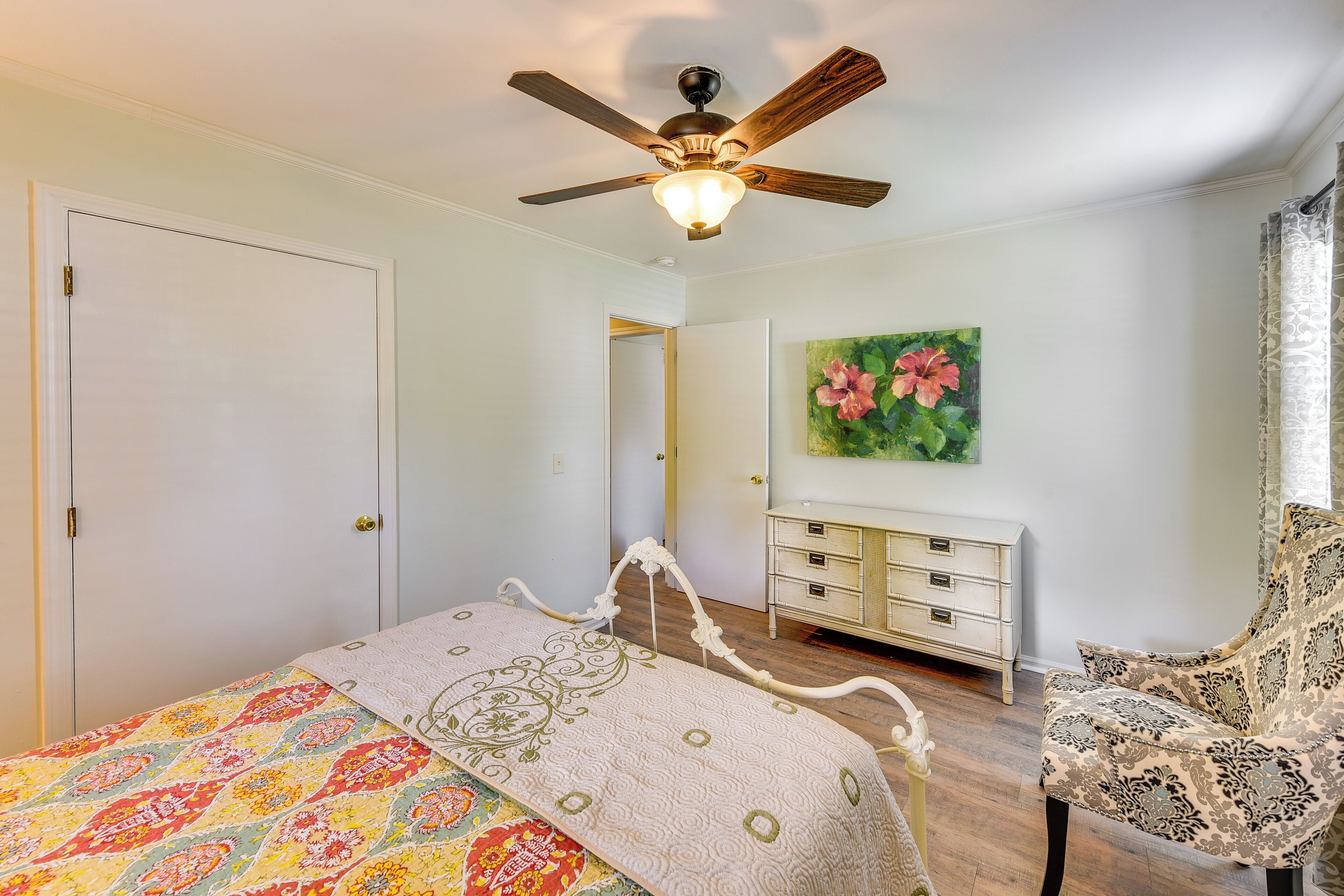 Un dormitorio con cama, ventilador de techo, cómoda y una silla.
