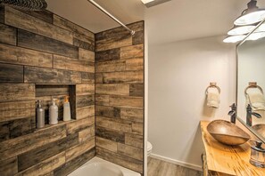 Relax in a serene space with a bathtub, wooden vanity, and shelf.
