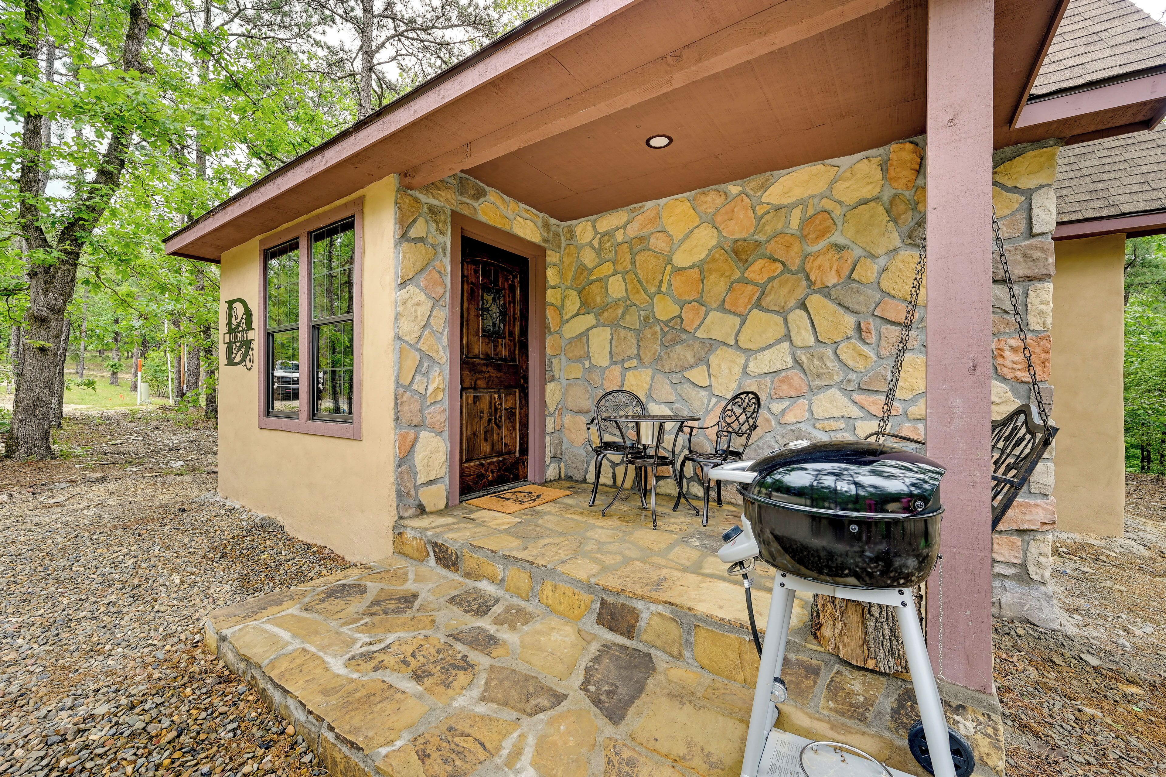 A stone building with a porch, a grill, and a door.