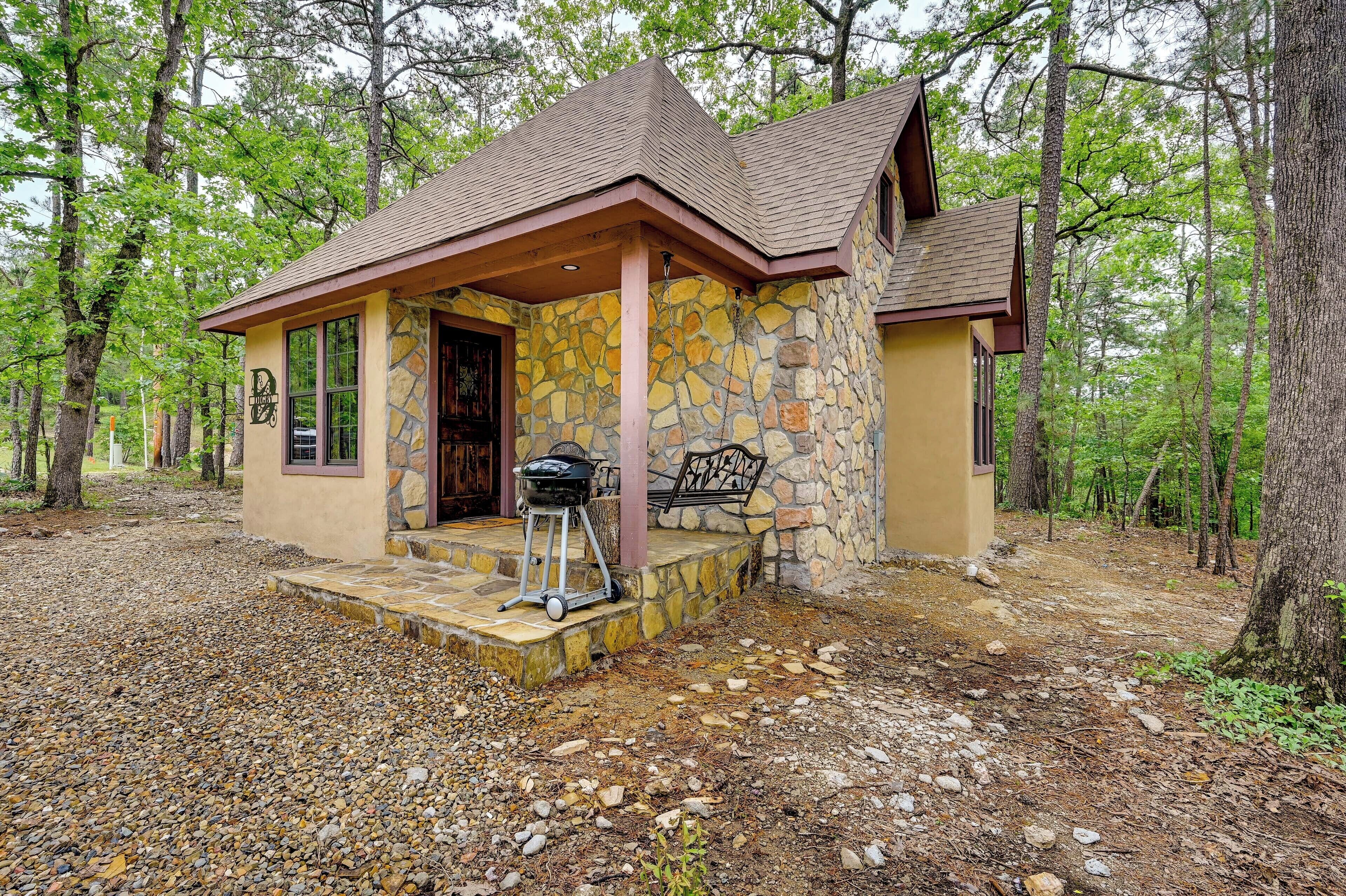 A small stone building with a porch and a grill outside.