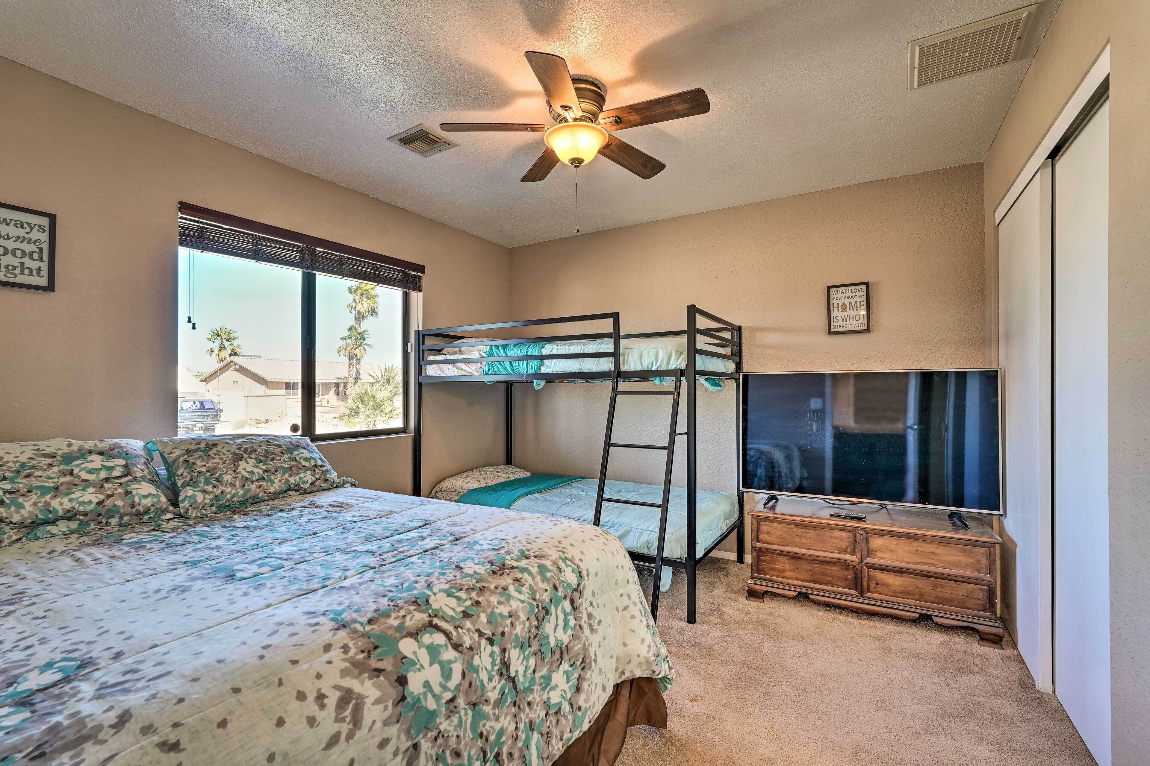 A bedroom with a bunk bed, a ceiling fan, a TV, and a dresser.