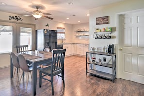 A modern kitchen with a dining area, wooden flooring, a ceiling fan, and a coffee station. - Charming Clovis Home w/ Covered Patio! (Clovis)