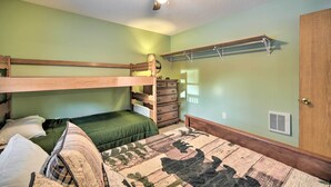 Ein Schlafraum mit Etagenbetten, Deckenventilator, Kommode und Wandregal.