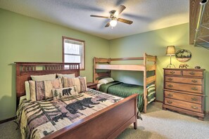 Ein Schlafzimmer mit Etagenbett, Kommode, Deckenventilator und Fenster.