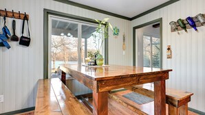 Ein Holztisch mit Bänken in einem Raum, dessen Wände ebenfalls aus Holz sind und ein großes Fenster vorhanden ist.
