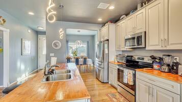 A modern kitchen with a wooden island, stainless steel appliances, and white cabinetry.