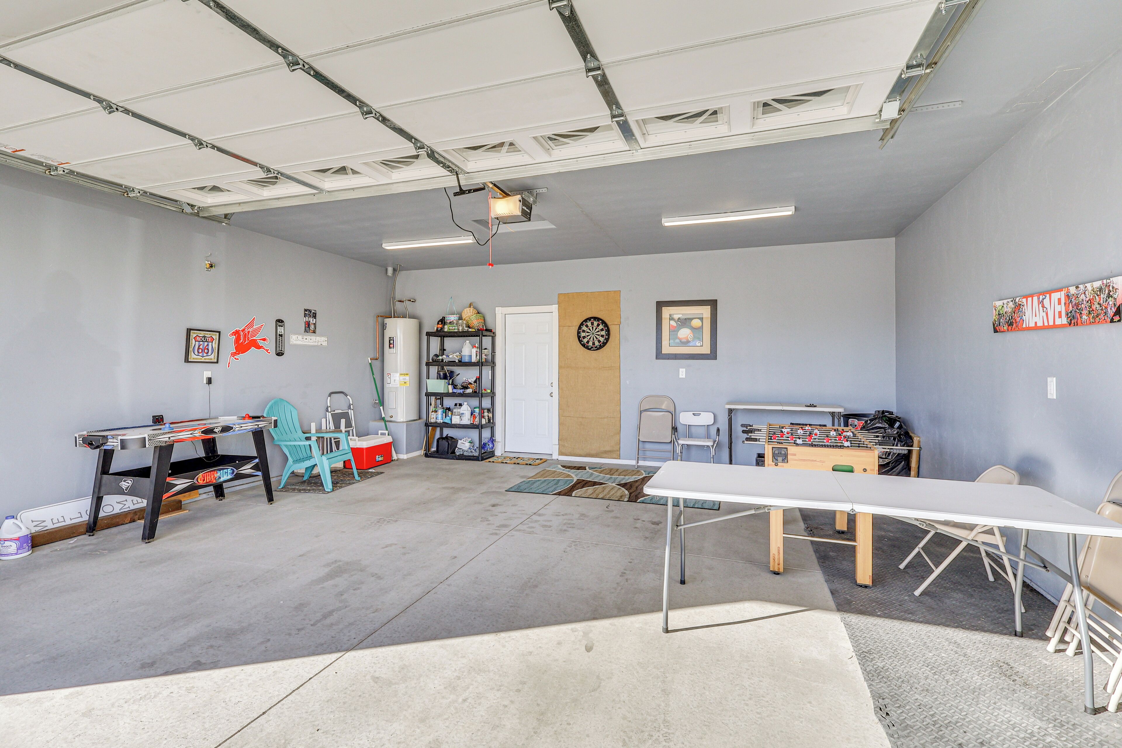 Una habitación amplia con una mesa larga, un dardo y una mesa de futbolín.