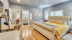 A bedroom with a large bed, a desk, and a chair. There is a dresser and a mirror in the room.