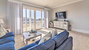 Un salon moderne avec un ensemble de canapés, une table basse et un téléviseur fixé au mur.