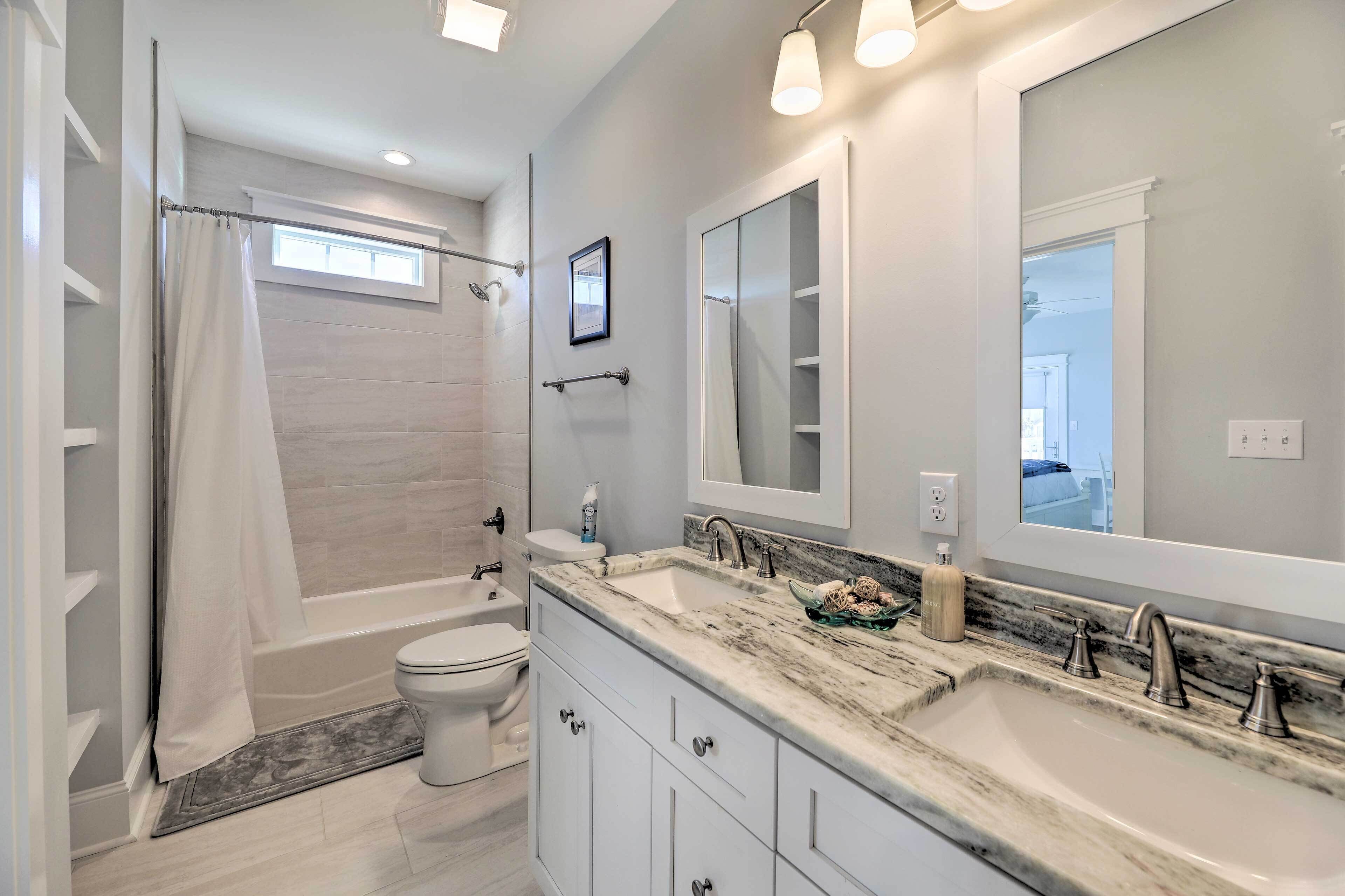 A modern bathroom with a bathtub, toilet, and double sink vanity.