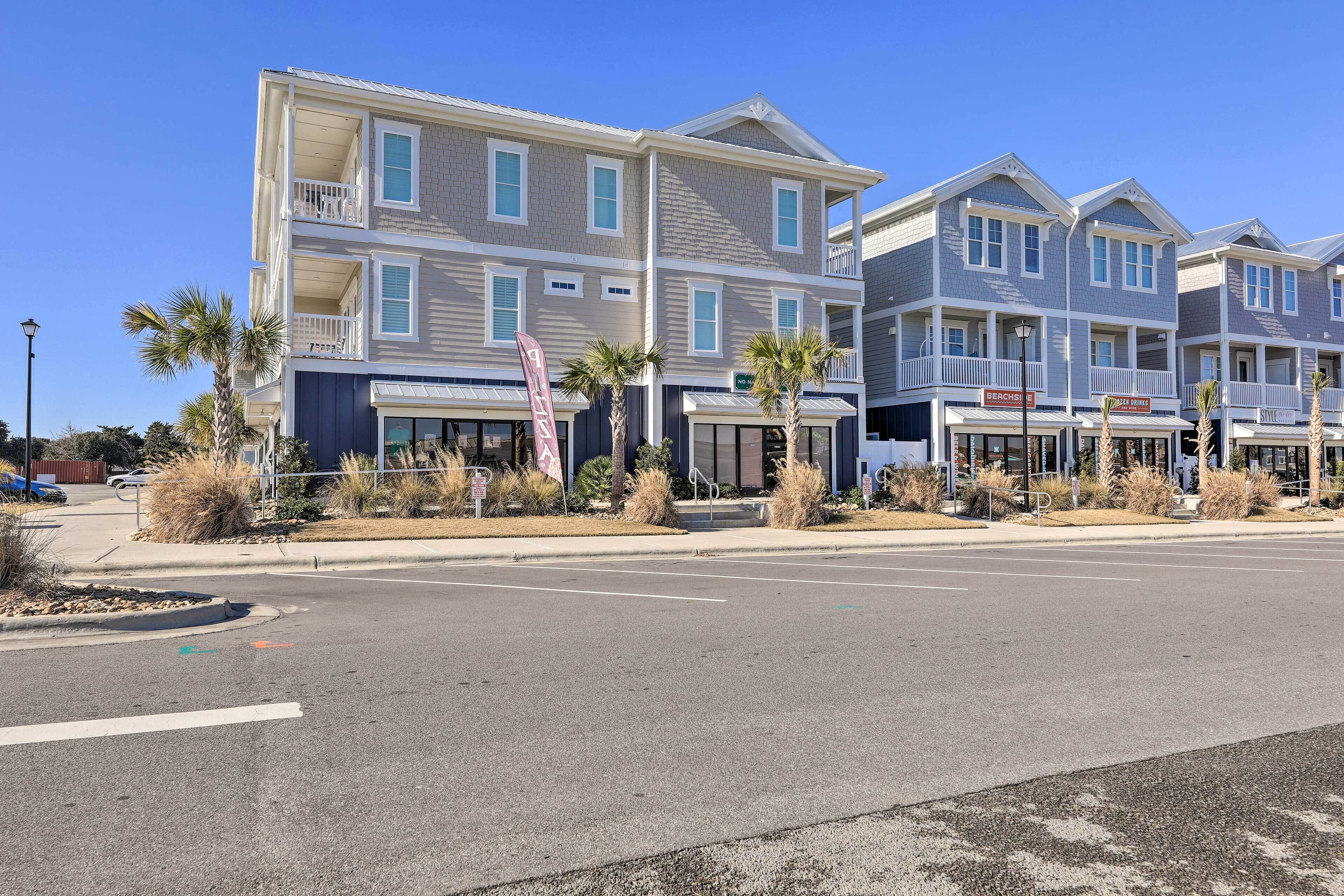 A multi-story hotel with balconies, a parking lot, and palm trees.