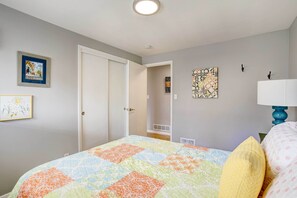 Ein Schlafzimmer mit einem Bett, einer Tür, einer Wandlampe und zwei gerahmten Bildern.
