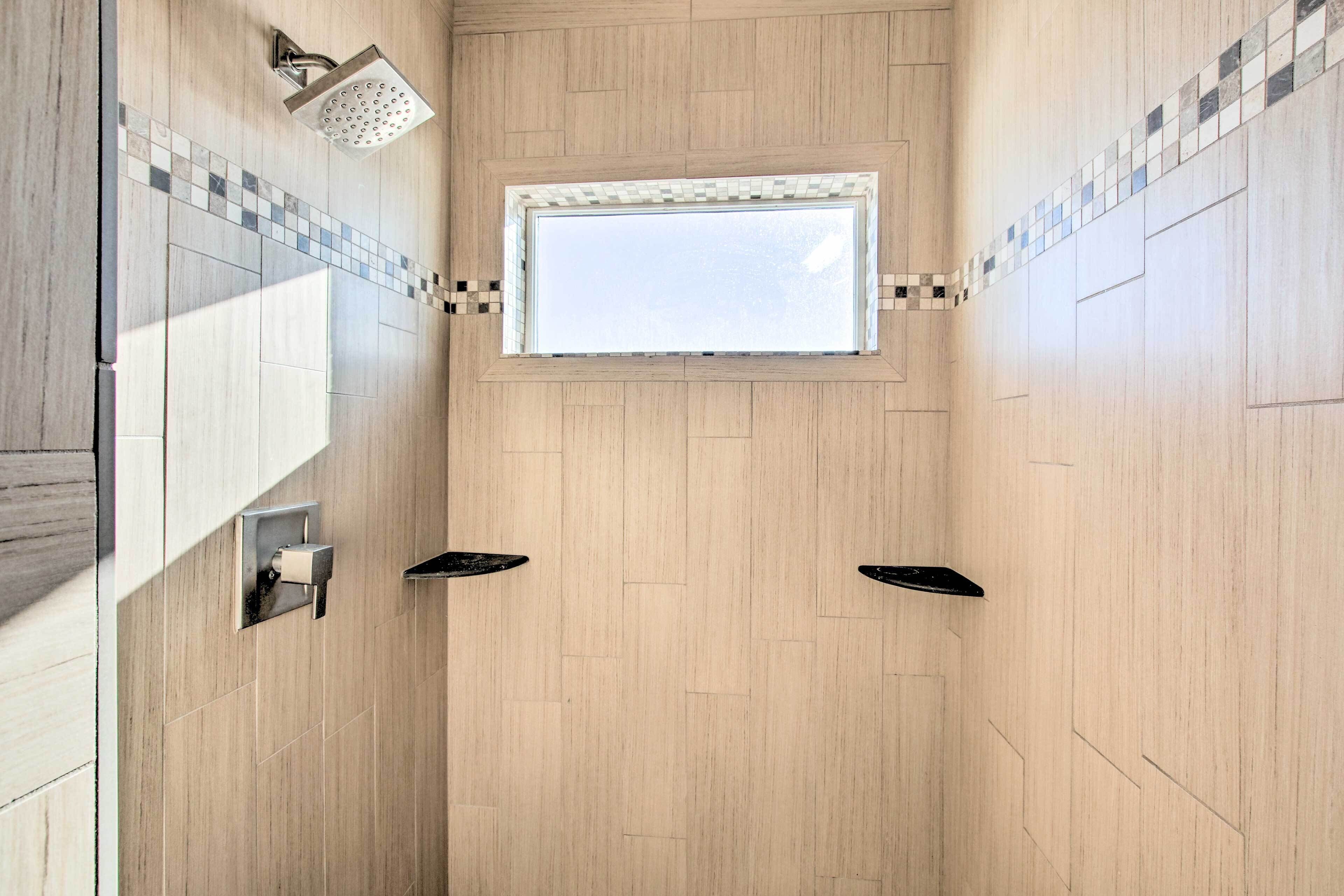 A modern shower with a skylight, wooden walls, and black fixtures.