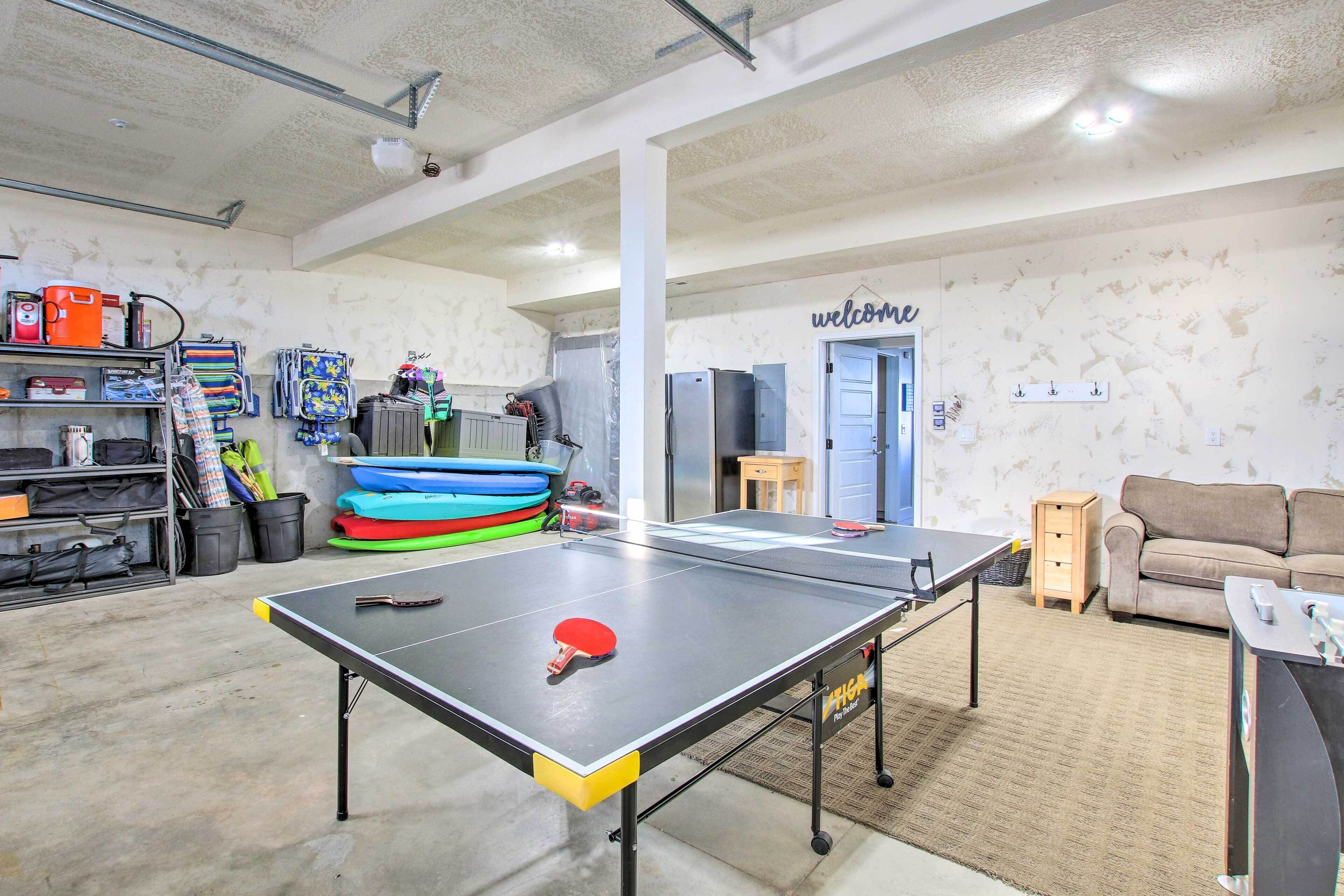 Une table de ping-pong dans une pièce où se trouvent un canapé, une petite table et un panneau indiquant « Bienvenue » sur le mur.