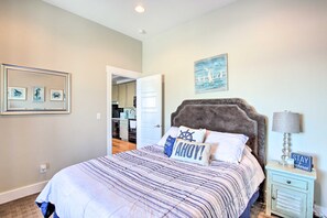 A bedroom with a bed, a nightstand, a lamp, and a wall with nautical-themed decor.