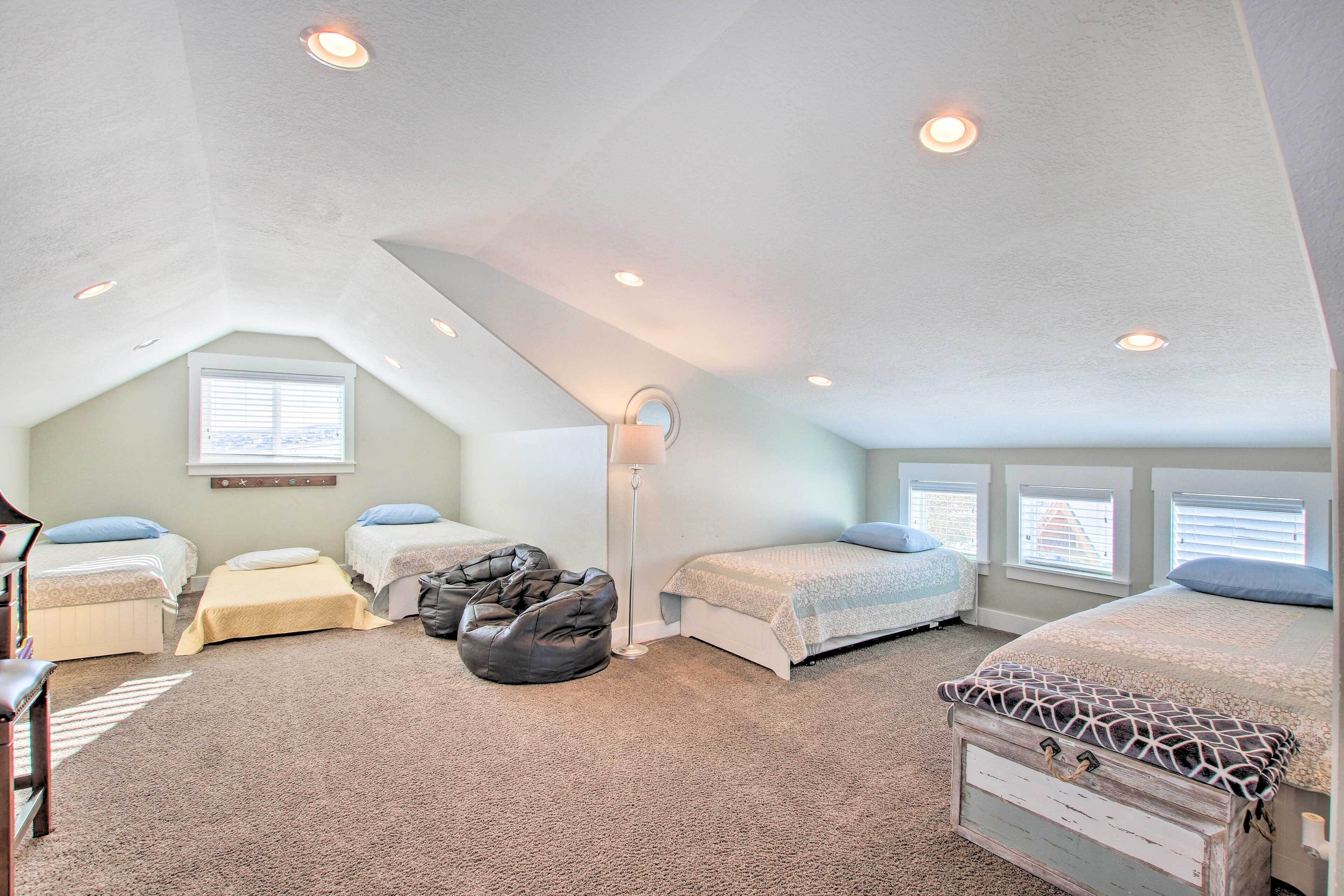 A bedroom with two beds, a desk, a chair, and a bean bag.