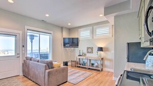 A living room with a sofa, a TV, and a console table with decorative items. - Garden City Gem: Private Hot Tub & Game Room! (Garden City)
