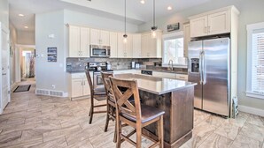 A spacious kitchen with a large island, stainless steel appliances, and wooden chairs. - Garden City Gem: Private Hot Tub & Game Room! (Garden City)