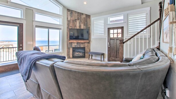A spacious living room with a large curved leather sofa, a fireplace, and a television. - Garden City Gem: Private Hot Tub & Game Room! (Garden City)