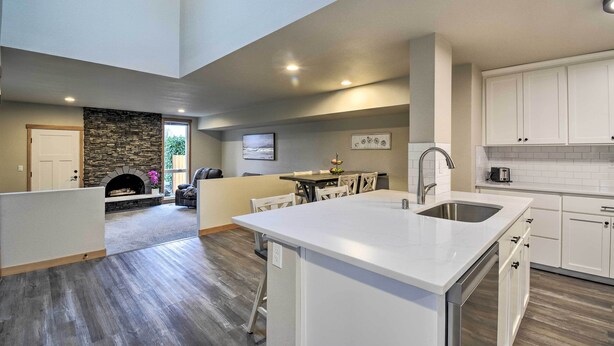 A spacious kitchen with a central island, white cabinetry, and a stone fireplace. - Luxurious Tacoma Retreat w/ Quartz Countertops! (Puyallup)