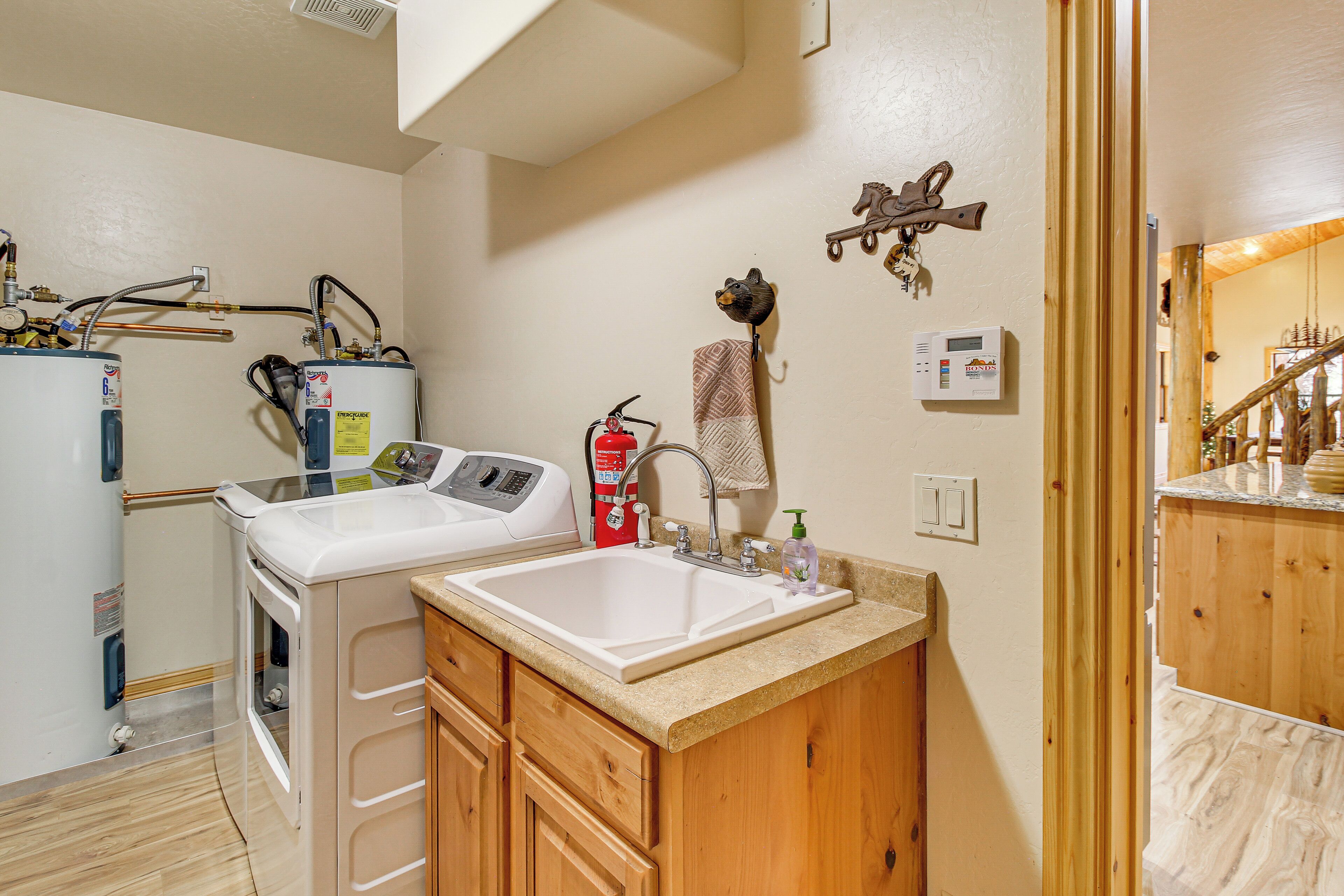 A compact kitchen with a built-in washer and dryer, wooden cabinets, a large sink, and a small countertop.