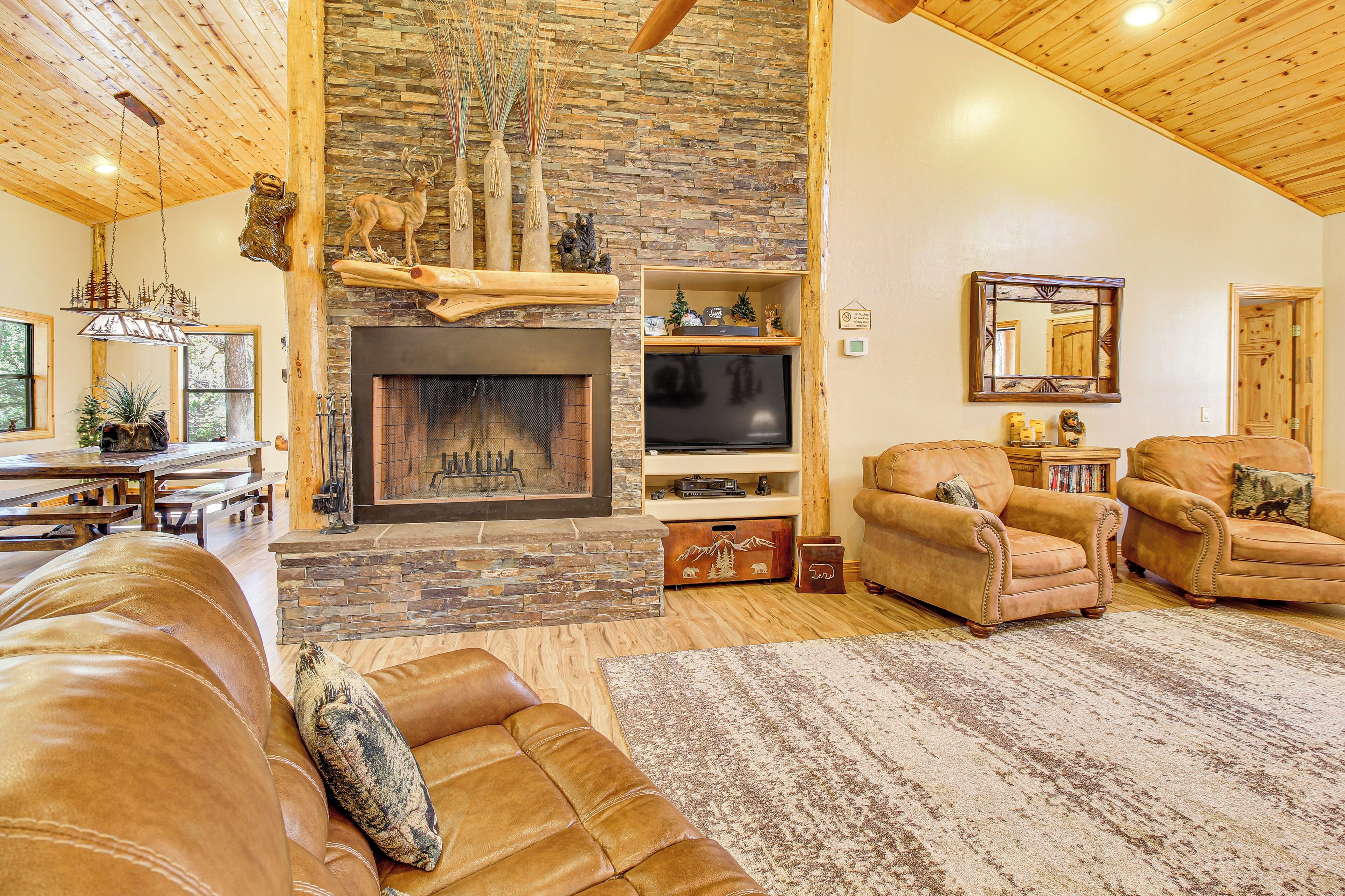 A spacious living room with a stone fireplace, leather sofas, and a television.