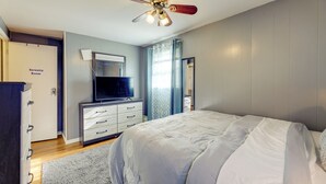 Een slaapkamer met een bed, een plafondventilator, een televisie, een dressoir en een deur met de tekst 