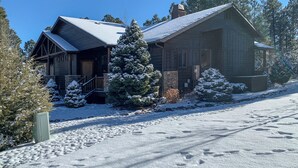 A log cabin with a snow-covered roof, a wooden porch, and a snow-laden evergreen tree in front. - Fireside Comfort & Family Fun: Wooded Show Low Gem (Show Low)