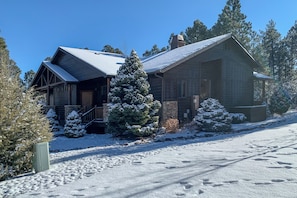 A log cabin with a snow-covered roof, a wooden porch, and a snow-laden evergreen tree in front. - Fireside Comfort & Family Fun: Wooded Show Low Gem (Show Low)