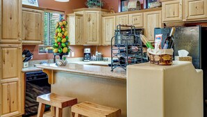 A kitchen with wooden cabinets, a coffee maker, a wine rack, and a refrigerator. - Fireside Comfort & Family Fun: Wooded Show Low Gem (Show Low)