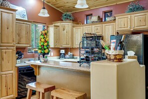 Una cocina con armarios de madera, cafetera, estante para vinos y refrigerador.