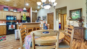 A kitchen with wooden cabinets, a stove, and a dining area with a wooden table and chairs. - Fireside Comfort & Family Fun: Wooded Show Low Gem (Show Low)