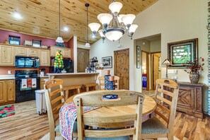 Una cocina con armarios de madera, una estufa y un comedor con una mesa y sillas de madera.